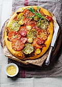 A pizza with various different tomatoes and rocket