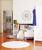 Runder weisser Teppich auf Parkettboden in modernem Schlafzimmer, im Hintergrund offene Tür mit Blick in den Gang
