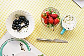 Bowls of blueberries, strawberries and cream cheese on a checked tablecloth