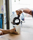 Arbeiter gießen Kaffee in einen Becher im Kaufhaus