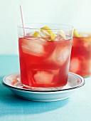 Cranberry drink with ice cubes and lemon zest