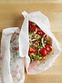 Fish fillet with tomatoes, olives and onions in parchment paper