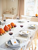 A table laid for Thanksgiving decorated with pumpkins and onions with glasses of red wine at each place