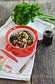 Runner bean salad with turkey bologna sausage in a red ceramic pot