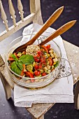 Panzanella (Italian bread salad) in a glass bowl with wooden salad servers