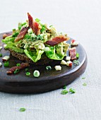 A slice of wholemeal bread topped with salad and bacon