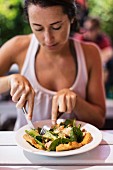 A woman eating a salmon salad in a garden restaurant