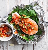 Raw salmon steak with tomatoes and baby spinach in aluminium foil (local)