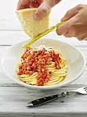 Cheese being grated over spaghetti bolognese