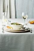 A table laid with creamy soup, water and wine