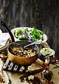 Pilzgemüse mit Sojasprossen und Kichererbsen in Kupferkasserolle, dahinter grüner Salat