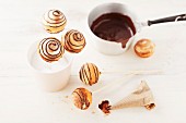 Marble cake pops being decorated with chocolate glaze