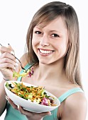 A sporty young woman eating a mixed leaf salad