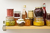 Jars and bottles of preserves and pickles on a wooden shelf