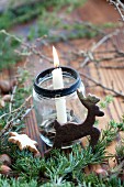 Christmas arrangement of candle in jam jar and reindeer-shaped biscuit