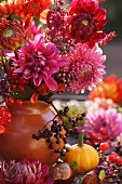 Bouquet of red dahlias with sprig of berries in vase