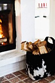 Logs in animal-skin bag next to fire in masonry fireplace