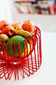 Fruit in bowl made of red, curved wire