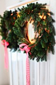 Christmas wreaths of fir branches and ribbons hanging on cupboard door