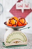 Orangen mit gespickten Nelken in Stern- und Herzform auf Retro Küchenwaage
