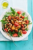 A rocket salad with chickpeas, tomatoes and pork