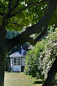 Round summer house with lattice windows in summer garden