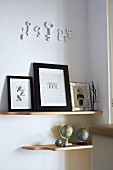 Collection of globes and framed pictures on wooden, wall-mounted shelves below ornamental keys on wall