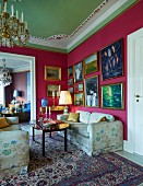 Sofa set with floral upholstery in corner of grand lounge with gilt-framed pictures on deep pink walls