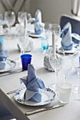 Festively set table with white and blue linen napkins on plates and various wine glasses