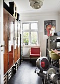 Offene Tür und Blick in Werkstatt-Raum, Vintage Leuchten auf Boden, gegenüber altem Einbauschrank, im Hintergrund Retro Sessel am Fenster