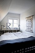 Französisches Bett mit weisser Bettwäsche und dunkler Tagesdecke vor Regal an Wand unter Fenster im Dachgeschoss