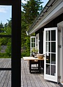 Table on wooden desk adjoining house with open, white lattice doors in rustic setting