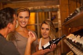 Junge Frauen lassen sich beim Weinkauf beraten
