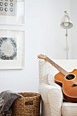 Guitar on armchair in front of retro standard lamp in corner