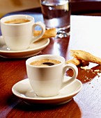 Three espressos, salted breadsticks and coffee beans on a table