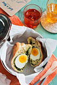 A bread roll filled with egg and spinach in a bread basket