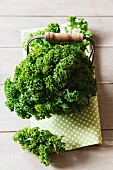 Green kale in a wire basket on a tea towel on a wooden table