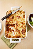 Lasagne in a baking dish with a slice cut out