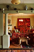 View through wide, open doorway with pillar; stuffed monkey against back of sofa with vintage floral pattern in artistic interior