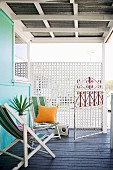 Chill-out zone - striped deckchairs on dark wooden floor of veranda with white lattice wooden screen