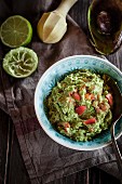 A bowl of guacamole, a hollowed out avocado and a pressed lime half