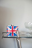 Flachmann mit Unionjack-Motiv und Cocktailgläser auf Glas-Beistelltisch