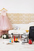 Wedding present ideas - espresso machine and colourful glasses on wooden floor in front of vintage chaise longue next to wedding dress hanging from coathanger on wall