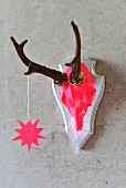 Hunting trophy painted neon pink with star pendant hanging on concrete wall