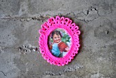 Vintage picture of little girl in neon pink crocheted frame on concrete wall
