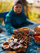 A child with venison skewers at an autumn picnic in a forest