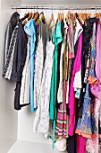 Women's clothing on hangers on rail in open wardrobe