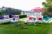 White outdoor furniture with red, white and blue accessories in front of pool; croquet set in foreground on lawn in luxurious gardens
