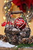 Basket of pine cones and red Christmas bauble with fly agaric ornaments in background