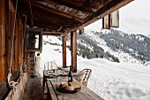 Bread and cheese on rustic wooden table outside cabin with view of winter mountain landscape